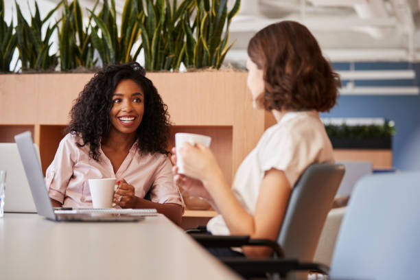 istock Two Businesswomen Working At Table In Modern Open Plan Office Drinking Coffee Together 1132005958