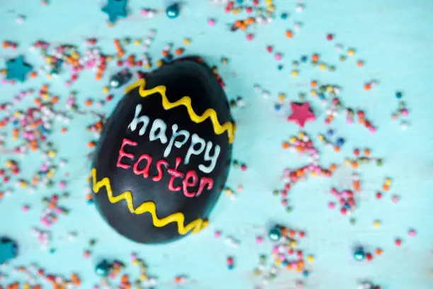 Top view of chocolate egg written with happy Easter text on wooden the table