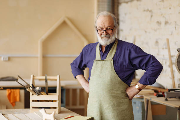 cheerful senior citizen is ready to work cheerful senior citizen is ready to work in the workshop. hardworking grandpa in the home workshop carpenter portrait stock pictures, royalty-free photos & images