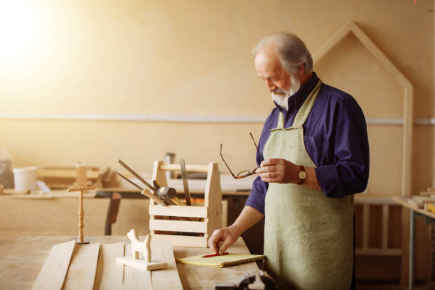 istock old male in special working outfut is putting red pencil on table 1132006084