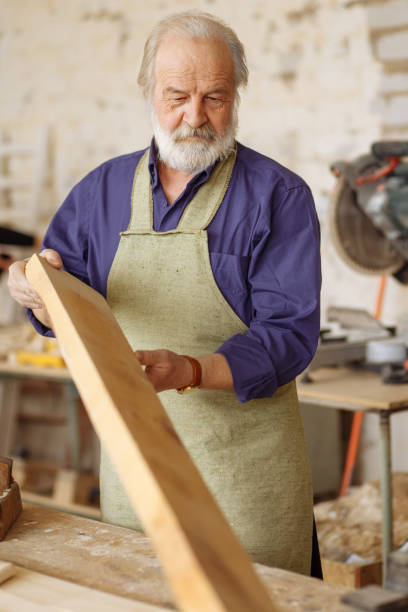 istock old nice carpenter with wooden plank at work 1132008051