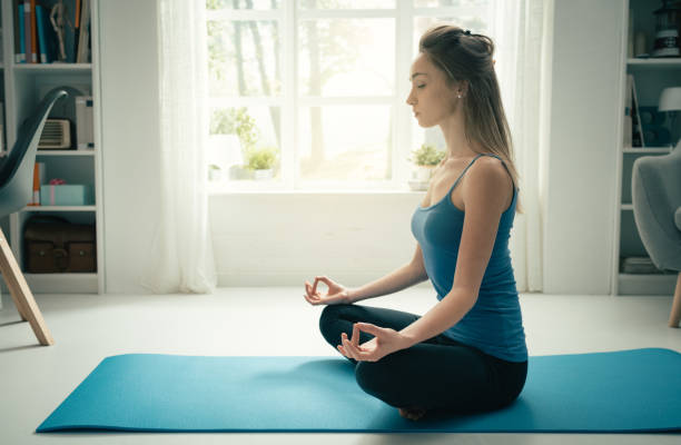 istock Young confident woman practicing mindfulness meditation at home, she is sitting with crossed legs on a mat 1132009922
