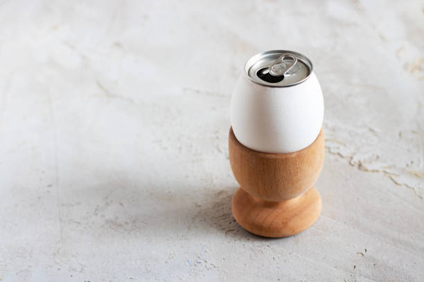 istock White egg with opened alluminium can in wooden egg cup on grey cement textured background, Horizontal banner, Copy space, Breakfast, Creative, Concept, Minimal, Easter, Lemonade, Fizzing 1132010027