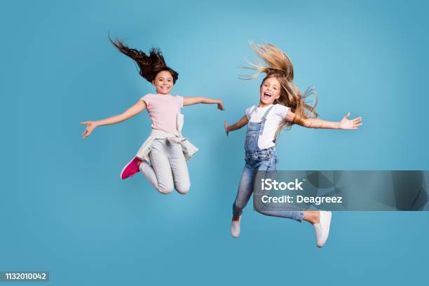 Full Length Body Size View Of Two People Nice Lovely Attractive Cheerful Straighthaired Preteen Girls Having Fun Day Daydream Yes Goal Achievement Free Time Isolated On Blue Background Stock Photo - Download Image Now