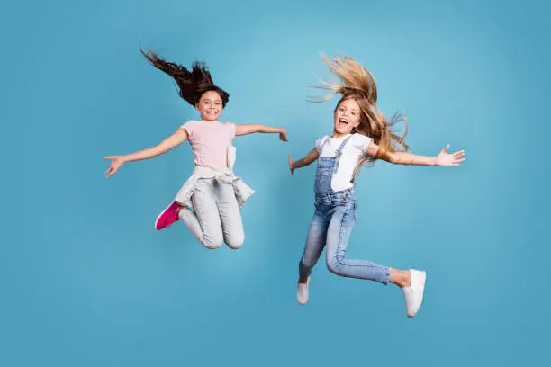 Photo of Full length body size view of two people nice lovely attractive cheerful straight-haired pre-teen girls having fun day daydream yes goal achievement free time isolated on blue background