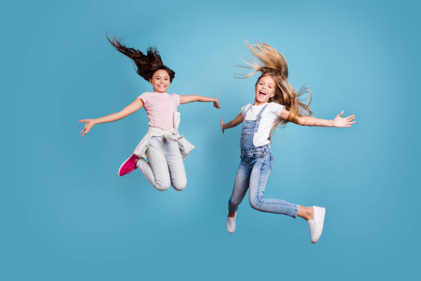 full length body size view of two people nice lovely attractive cheerful straight-haired pre-teen girls having fun day daydream yes goal achievement free time isolated on blue background - aspirations what vacations sport imagens e fotografias de stock