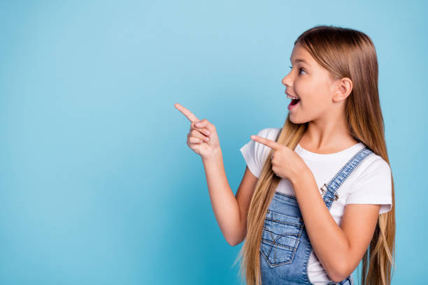 close-up profile side portrait of her she nice cute attractive cheerful amazed glad straight-haired blonde girl pointing two fingers looking aside copy space isolated on blue pastel background - aside imagens e fotografias de stock