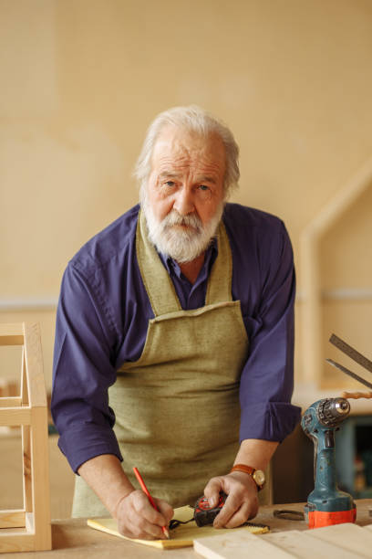 istock mature old craftsman with white beard, moustache nad hair developing a design 1132010932