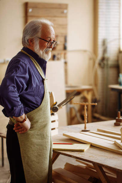 istock old carpenter standing with hands on hips after finishing his hard work 1132011040