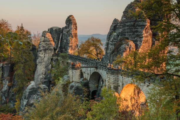 puente de bastei en el sol de la tarde con formación de rocas y cubierta de árbol en el estado de ánimo otoño - basteifelsen fotografías e imágenes de stock