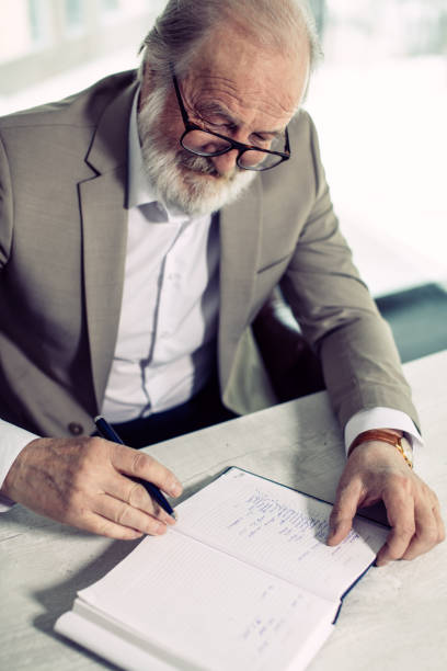 istock smiling old man is writing his memories from his happy youth on the notebook 1132012849