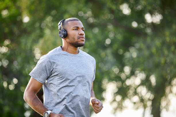 istock Man listening music while jogging at park 1132013074