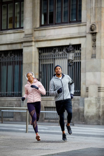 istock Confident young couple jogging against building 1132014162
