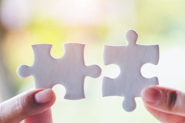 istock Closeup hand of connecting jigsaw puzzle to complete the mission with sunlight effect, Business solutions, success and strategy concept 1132014183