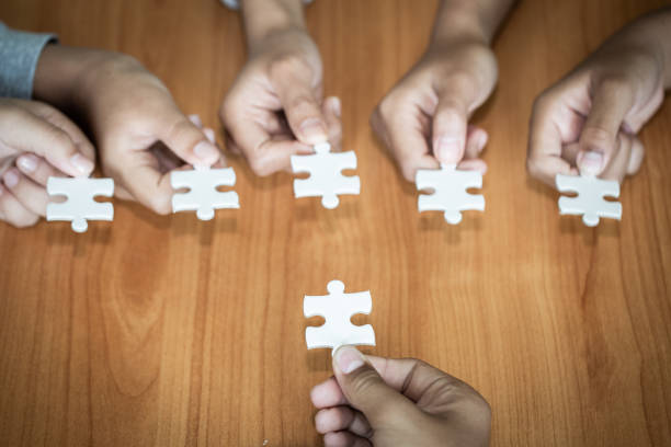 istock Hands of diverse people assembling jigsaw puzzle, team put pieces together searching for right match, help support in teamwork to find common solution concept, top close up view 1132014184