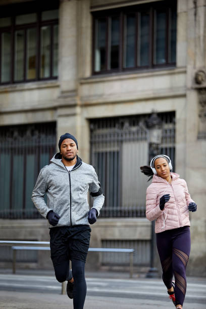 istock Confident man and woman jogging against building 1132014207