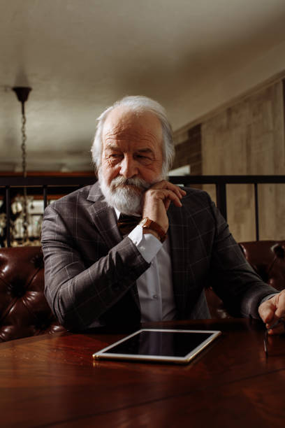 reflexivo anciano rico sentado en la mesa - human eye tired rubbing businessman fotografías e imágenes de stock