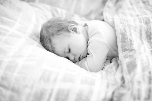 adorable niña pequeña durmiendo en la cama. tranquilo niño tranquilo soñando durante el día de sueño. hermoso bebé en la cama de los padres. dormir juntos concepto. - party newborn baby hospital fotografías e imágenes de stock