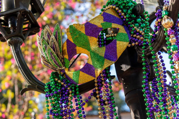 Outdoor Mardi Gras beads and mask on light post Outdoor Mardi Gras beads and mask on light post in sunshine parade stock pictures, royalty-free photos & images