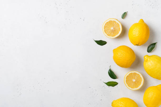los limones maduros yacen planos con hojas sobre fondo blanco - enfoque de objetos sobre la mesa fotos fotografías e imágenes de stock