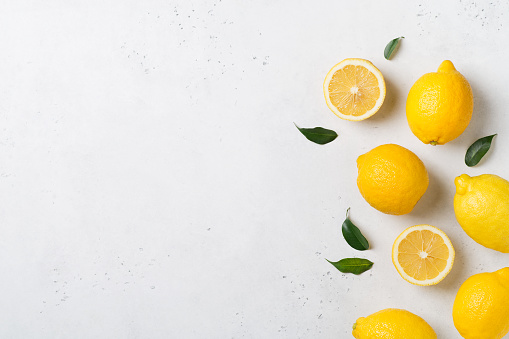 Ripe lemons flat lay with leaves on white background. Copy space, top view