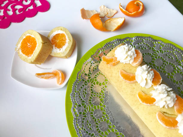 istock Cooking biscuit roll stuffed with ricotta and mandarin. Ready roll lies on a platter. Next on the saucer is a cut piece of roll. 1132020669