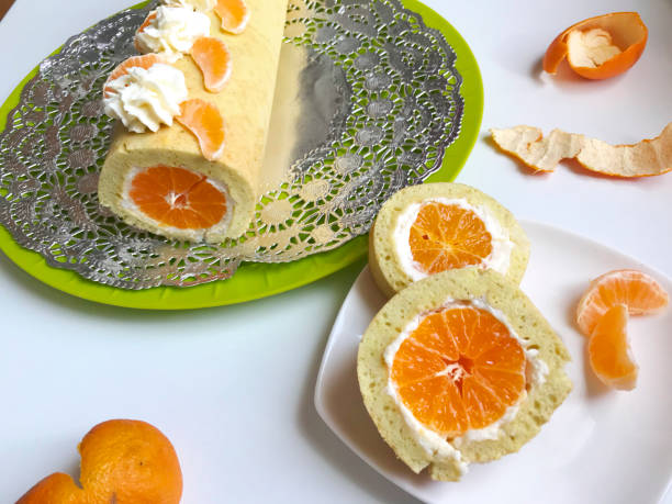 istock Cooking biscuit roll stuffed with ricotta and mandarin. Ready roll lies on a platter. Next on the saucer is a cut piece of roll. 1132020674