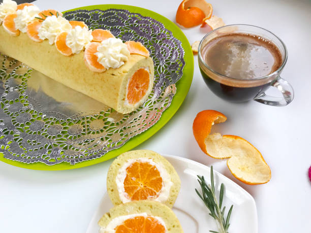 istock Cooking biscuit roll stuffed with ricotta and mandarin. Ready roll lies on a platter. Next on the saucer is a cut piece of roll. 1132020676