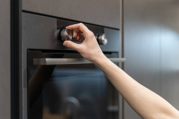 istock Side view photo of woman hand tuning program on control panel for built-in oven in black kitchen cabinet 1132021478