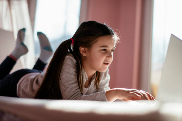 istock Smiling little girl using laptop in bed. 1132022059