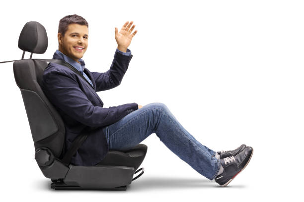 Full length shot of a young man in a car seat with a fastened seatbelt holding a steering wheel isolated on white background