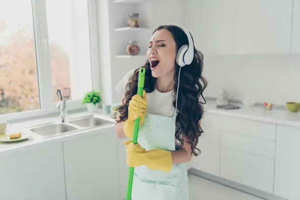 Photo of Portrait of her she nice beautiful lovely charming winsome house-wife using broom like mic singing popular song in modern light white interior indoors