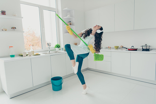 Full length body size portrait of her she nice adorable beautiful cheerful wavy-haired house-wife using broom dancing having fun in modern light white interior indoors
