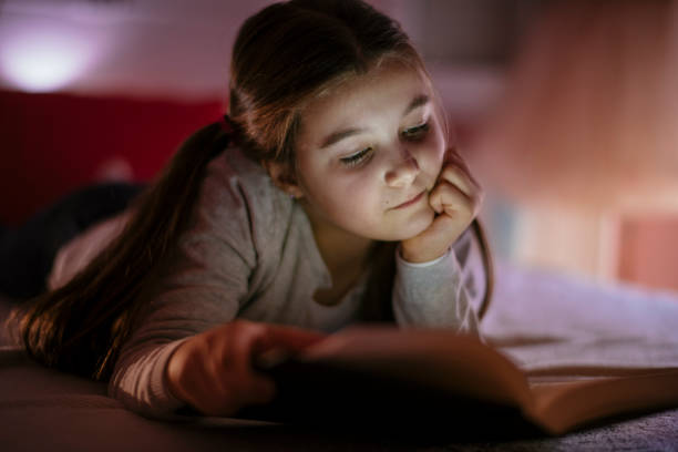istock Child girl reading book in bed 1132024013