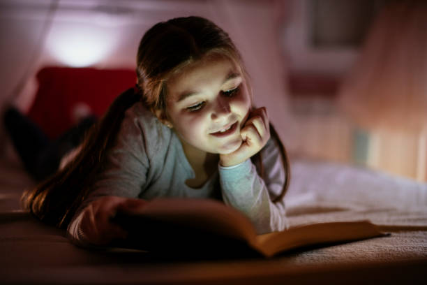 istock Child girl reading book in bed 1132025354