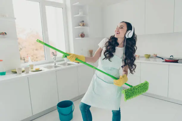 Photo of Portrait of her she nice cute lovely beautiful cheerful positive wavy-haired house-wife using broom dancing having fun fooling in modern light white interior indoors