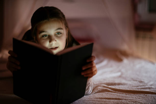istock Child girl reading book in bed 1132025763