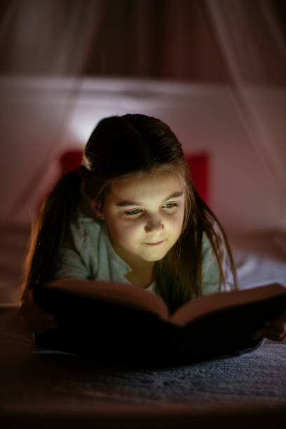 istock Child girl reading book in bed 1132025855