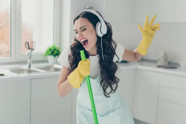 Photo of Full length body size portrait of her she nice beautiful lovely cheerful cheery funny wavy-haired house-wife using broom like mic fooling having fun in modern light white interior indoors