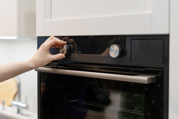 istock Closeup photo of woman hand switch program on control panel for built-in oven in white kitchen cabinet 1132032956