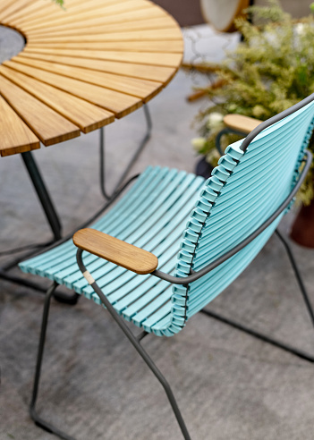 Vertical photo of blue garden chair standing outside near wooden elegant table