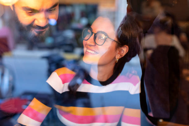 istock Young Couple Using a Laptop while Drinking Coffee or Tea at Cafe.The reflection from the glass Windows 1132038228