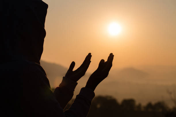 sylwetka młodych ludzkich rąk otworzyć palmę do kultu i modląc się do boga o wschodzie słońca, religii chrześcijańskiej tło koncepcji. - forgiveness praying men silhouette zdjęcia i obrazy z banku zdjęć