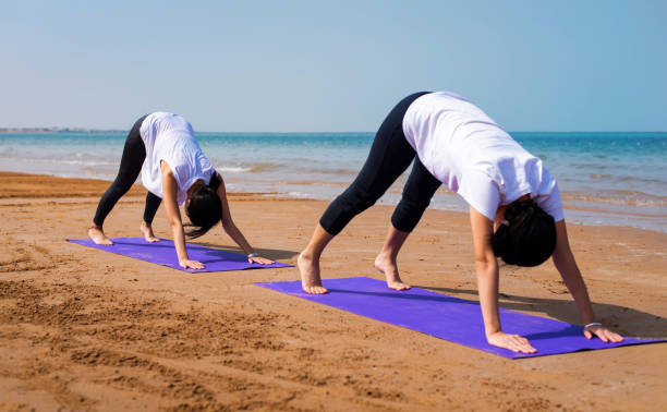 istock Women doing yoga on the beach 1132038469