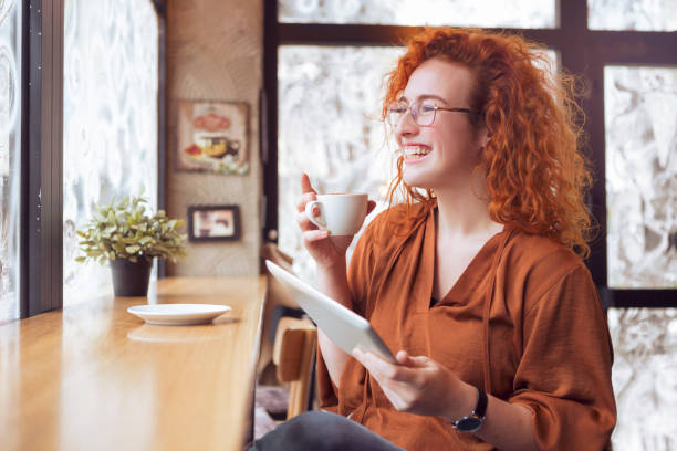 istock Redhead young woman with tablet drinking coffee 1132038766