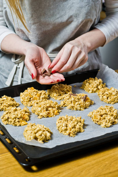 istock The chef is preparing cookies, spread the dough on the trays. Side view, black background, kitchen 1132039453