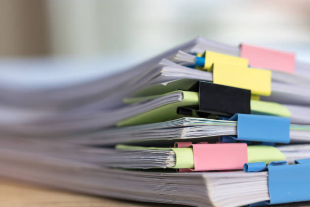 istock Close up stack of paperwork. Pile of unfinished homework assignment stacked in archive with colorful binder paper clips on table waiting to be managed and inspected. Education and business concept. 1132040786