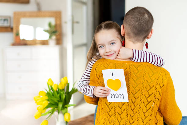 happy dzień matki lub tło urodzinowe. urocza młoda dziewczyna dając jej mama, młody pacjent raka, domowej roboty i love mom kartkę z życzeniami. koncepcja uroczystości rodzinnych. - mothers day tulip yellow greeting card zdjęcia i obrazy z banku zdjęć