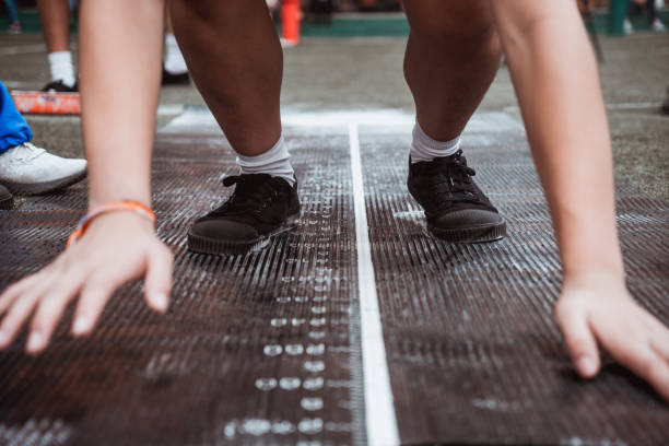 istock Students boy taking long jump on rubber board pid or sand pid during a school sport competition day. School sports day long jump competition. 1132042349