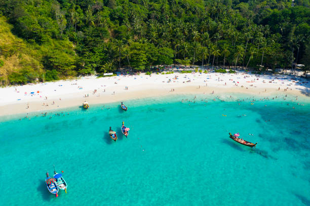 vue d'en haut, vue aérienne d'une belle plage tropicale avec du sable blanc et de l'eau claire turquoise, des bateaux longtail et des personnes bronzette, plage de la liberté, phuket, thaïlande. - phuket province thailand tourist asia photos et images de collection